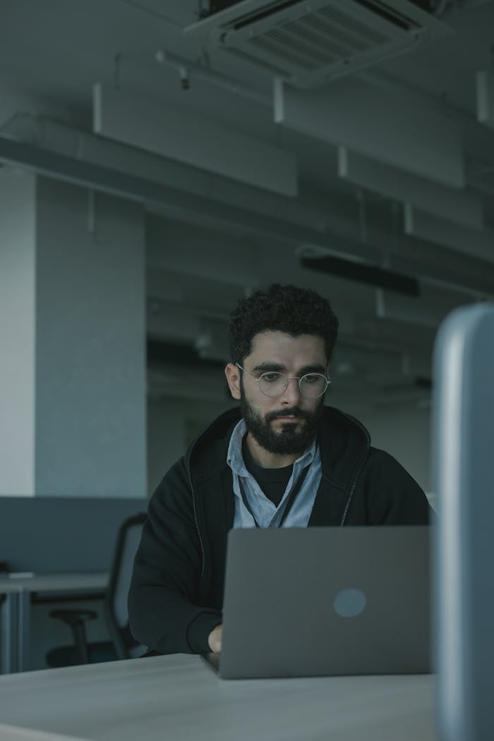 A focused man working on his laptop in a modern office setting.